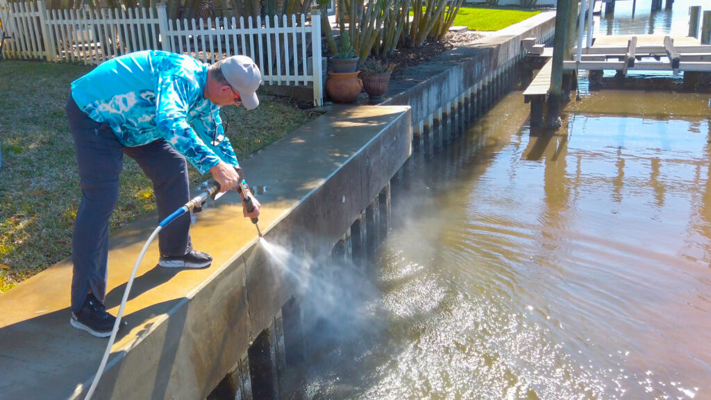 An image of a man using a hose to clean a seawall.